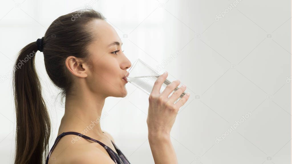 Healthcare. Girl drinking clean mineral water, side view
