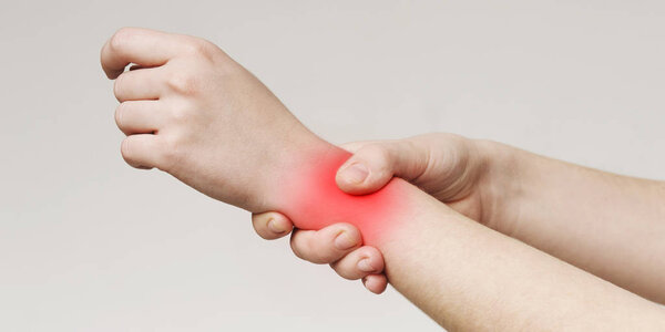 Woman holding her inflamed wrist with red sore zone