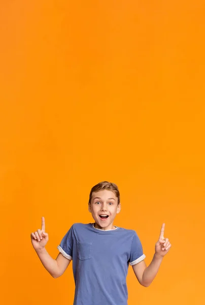 Erstaunt lächelnder Teenie-Junge zeigt mit zwei Fingern auf leeren Raum — Stockfoto