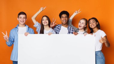 Boş afiş tutan mutlu arkadaşlar, turuncu arka plan