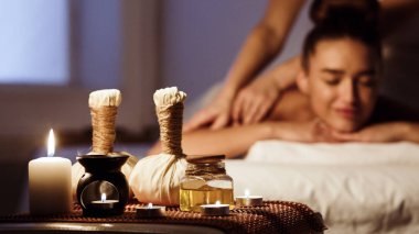 Ahşap tepsi üzerinde bitkisel çantalar ile Spa salonunda rahatlatıcı kadın