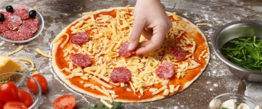 Şef mutfak masasında İtalyan pizza salam ekleme