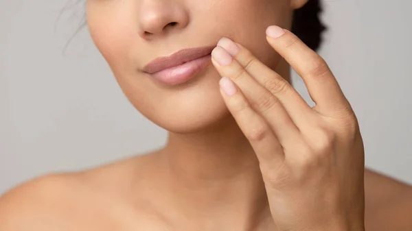 Mujer aplicando bálsamo labial sobre fondo gris —  Fotos de Stock