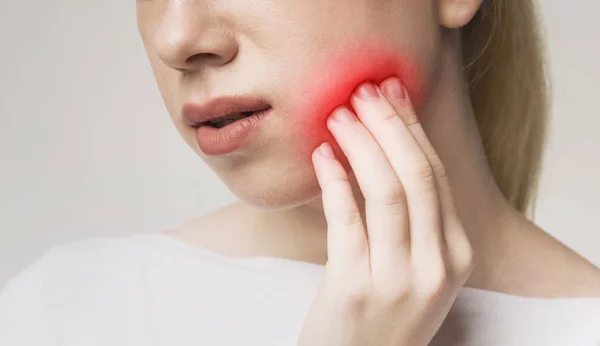 Kobieta cierpiąca na ból zęba, dotykająca podrażnionego policzka — Zdjęcie stockowe