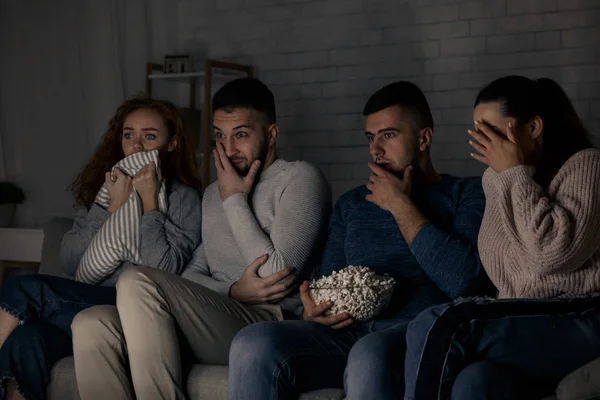 Frightened friends watching film and eating popcorn