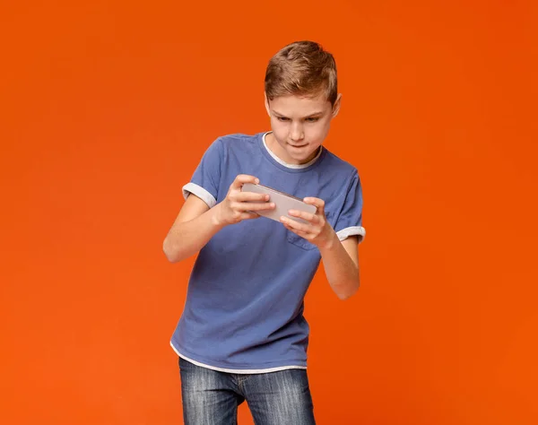 Мальчик держит мобильник и играет в видеоигры — стоковое фото
