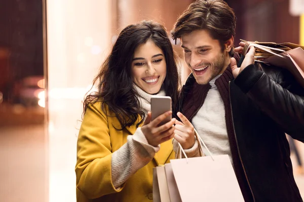 Concepto de venta y consumismo. Pareja con bolsas de compras y smartphone —  Fotos de Stock