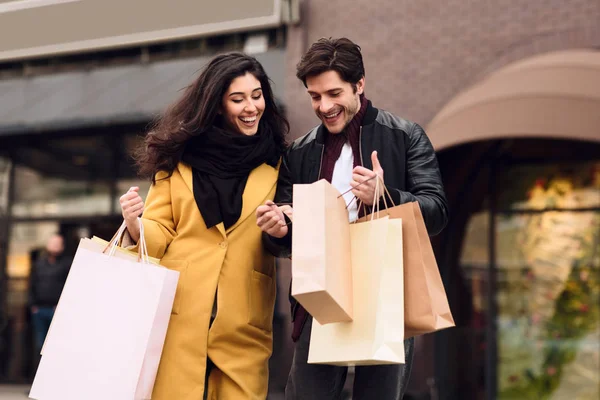 Loving couple looking into shopping bags outdoors — Stock Photo, Image