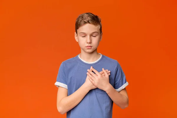 Sensitive teenage boy pressing hands to chest being grateful — Stock Photo, Image