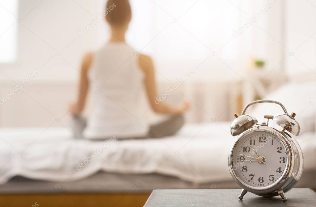 Yoga time. Woman meditating on bed in lotus pose