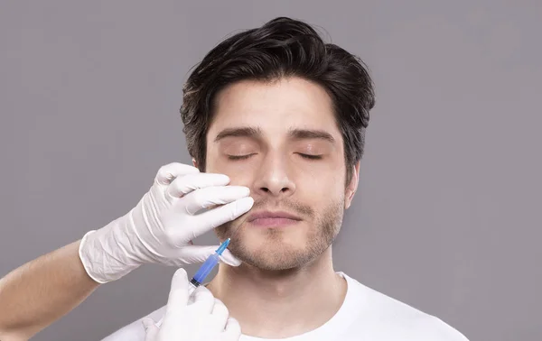 Millennial man getting hyaluronic collagen injection in clinic — Stock Photo, Image