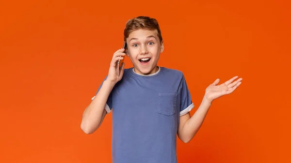 Förvånad pojke pratar på mobiltelefon, vinka händer och öppna munnen — Stockfoto