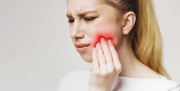 Разочарованная молодая женщина с зубной болью касается ее щеки
