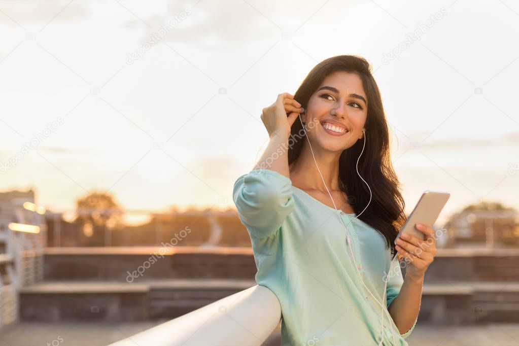 Enjoying free time. Girl listening music in earphones outdoors
