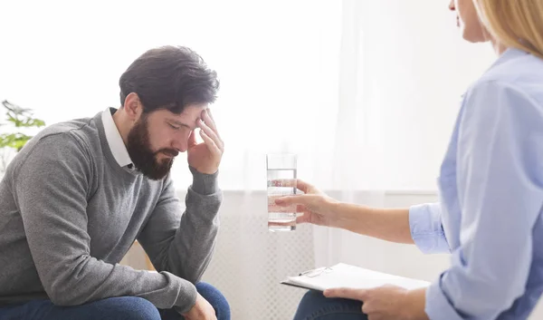 Psychanalyste offrant un verre d'eau à un patient masculin déprimé — Photo