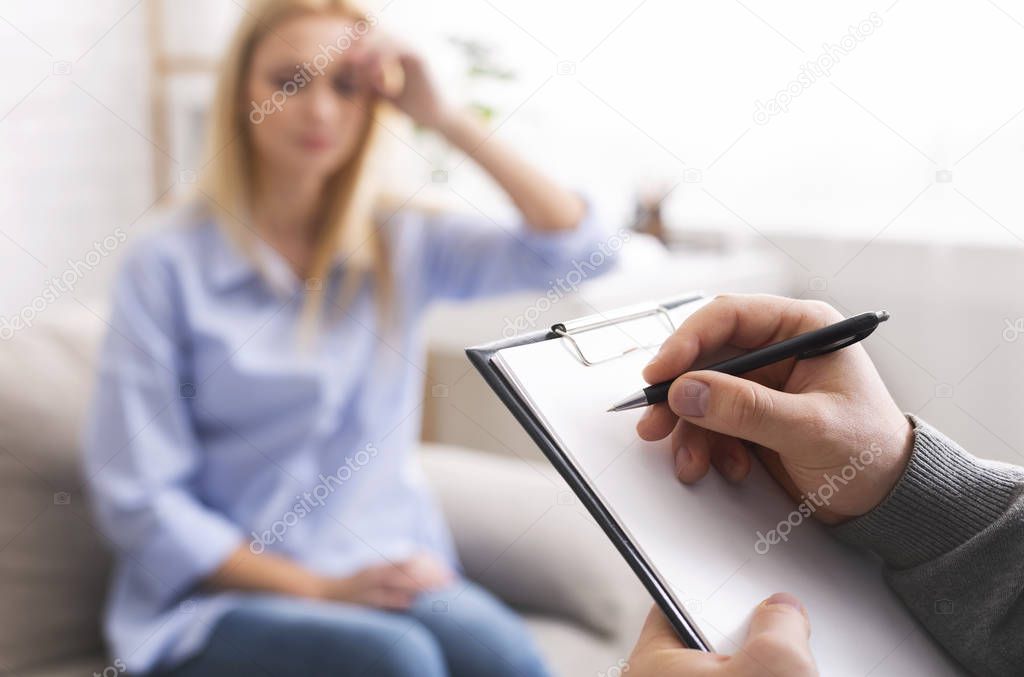 Depressed woman talking to psychotherapist, doctor taking notes