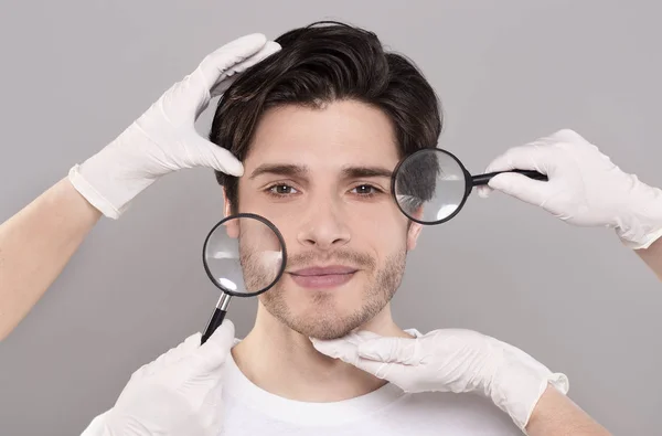 Arca fiatal jóképű férfi kozmetikusok kezében és Magnifiers — Stock Fotó