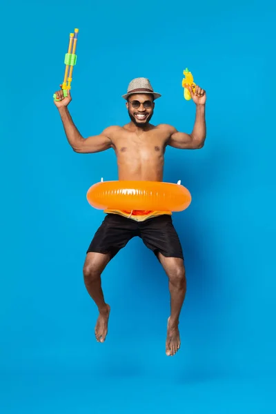 Alegre joven negro saltando con dos pistolas de agua —  Fotos de Stock