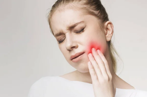 Молодая женщина страдает от зубной боли, трогает щеку — стоковое фото