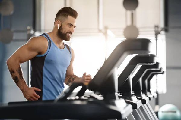 Junger schöner Mann läuft im Fitnessstudio auf Laufband — Stockfoto