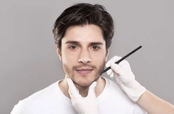 Kosmetyczki ręce oznakowanie męskiej twarzy przed operacją piękna — Zdjęcie stockowe