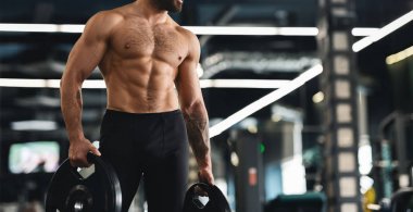 Çıplak gövde tutan barbell plakaları ile Kas atlet