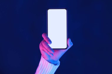 Kadın eli neon ışıklarda akıllı telefon ekranı gösteriyor
