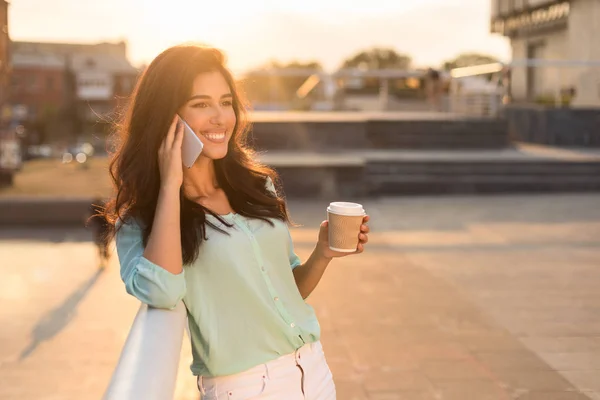 Charmante vrouw praten op telefoon lopen tijdens vrije tijd in de stad — Stockfoto