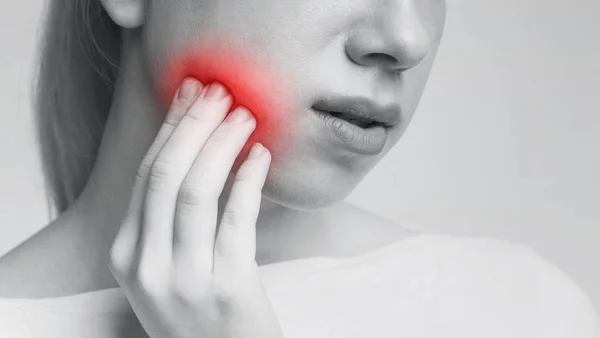 Jovem mulher sentindo dor de dente tocando sua bochecha — Fotografia de Stock