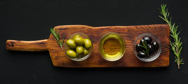 Olive oil and olives in bowls on board. — Stock Photo, Image