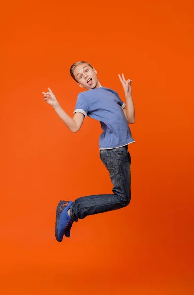 Pojke visar tungan och hoppa i luften — Stockfoto