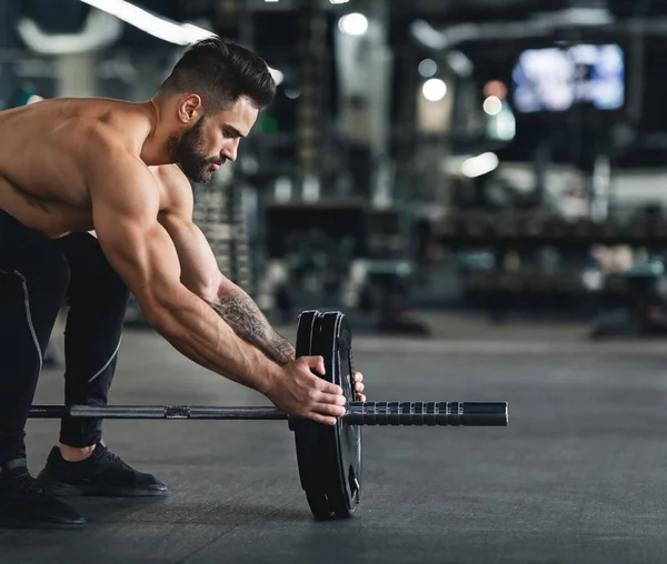 Uomo muscolare che cambia pesi del bilanciere, spazio vuoto — Foto Stock