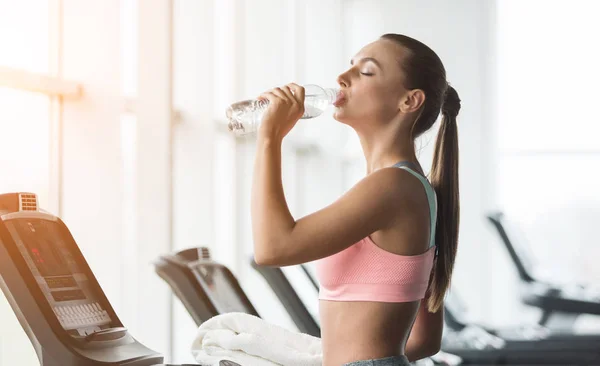 Descanse depois de correr. Mulher bebendo água, exercitando-se na esteira — Fotografia de Stock