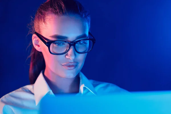 Night Online Work. Woman using laptop in colorful neon lights