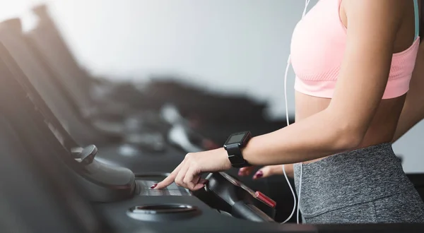 Menina ajustando a velocidade na esteira, fazendo exercício cardio — Fotografia de Stock