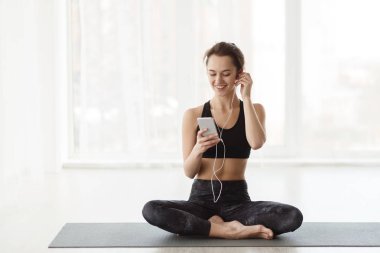 Yoga yaptıktan sonra kadın, akıllı telefonla dinleniyor.