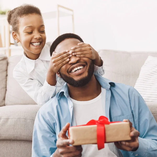 Menina fechando os olhos pais e dando caixa de presente — Fotografia de Stock