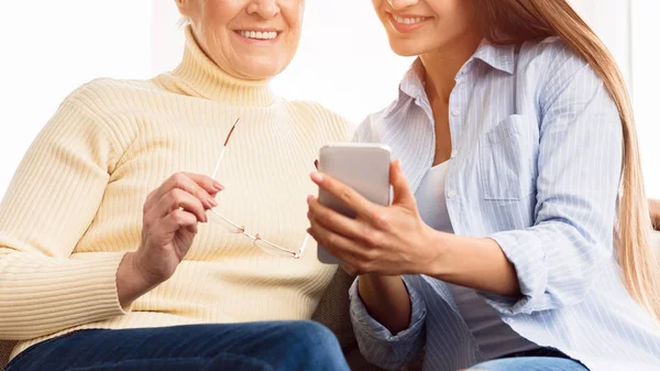Daughter showing photos to mother, using smartphone — Stock Photo, Image