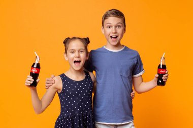Mutlu çocuklar portakal üzerinde pipetler ile Coca-Cola Classic içme