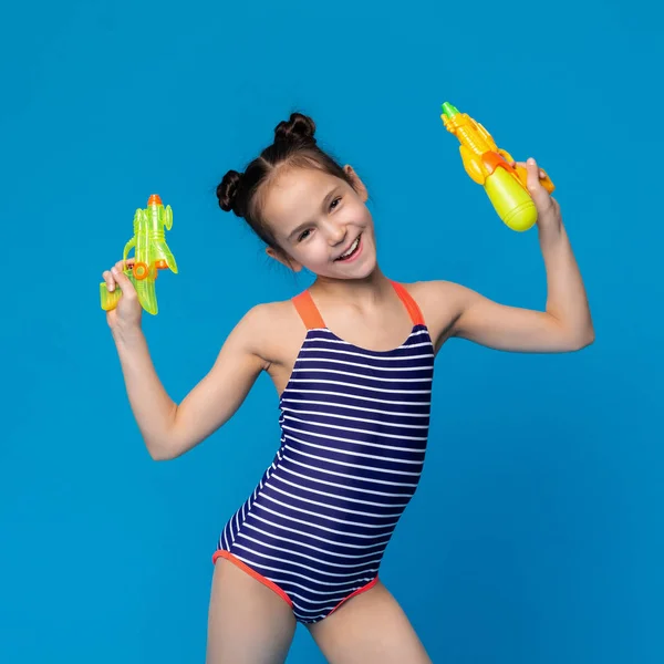 Kleines Mädchen im Badeanzug mit Wasserpistolen — Stockfoto