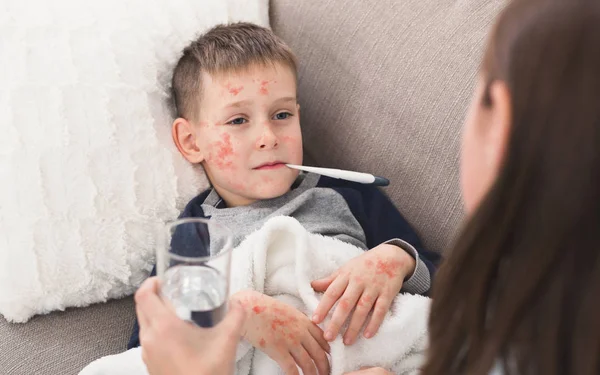 Παιδί αγόρι με την ιλαρά μέτρηση της θερμοκρασίας, που βρίσκεται στον καναπέ — Φωτογραφία Αρχείου