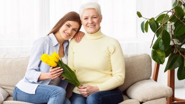 Çiçek buketi ile kıdemli anne ve genç kızı