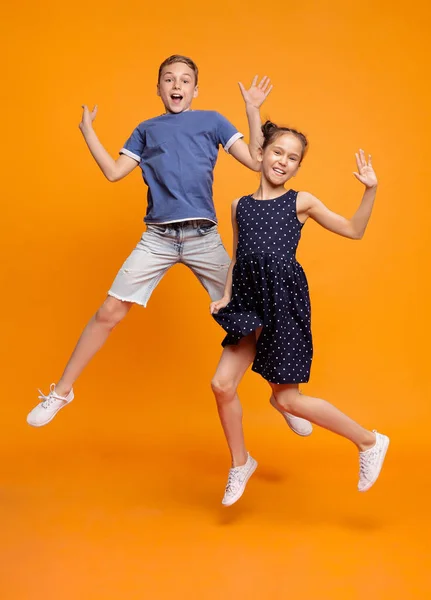 Fröhliche kleine Mädchen und Jungen springen vor Freude zusammen — Stockfoto