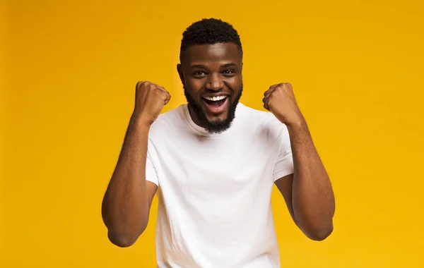 Excited african-american man shakes clenched fists at studio — Stock Photo, Image