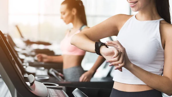 Chica en forma mirando smartwatch, marcando el tiempo de entrenamiento — Foto de Stock