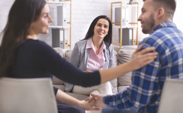 Smiling psychologist looking at lovely couple at therapy