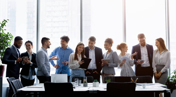 Business people standing against window, discussing work