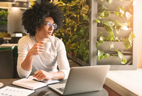 Jovem bonito trabalhando no laptop e sorrindo — Fotografia de Stock