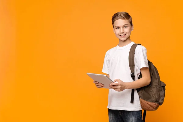 Schoolboy met rugzak met behulp van Tablet PC en glimlachend — Stockfoto