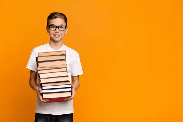 Sprytny nastolatek chłopiec w okularach trzyma stos książek — Zdjęcie stockowe
